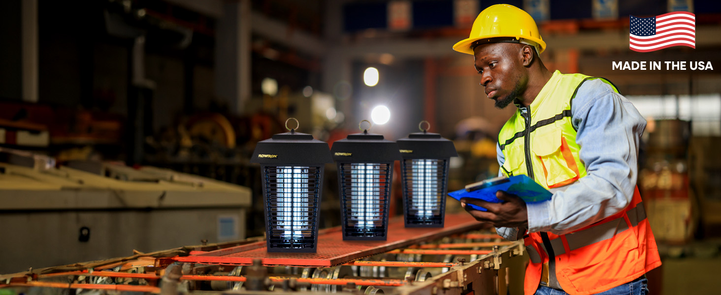 Male factory worker holding a clipboard inspecting three bug zappers